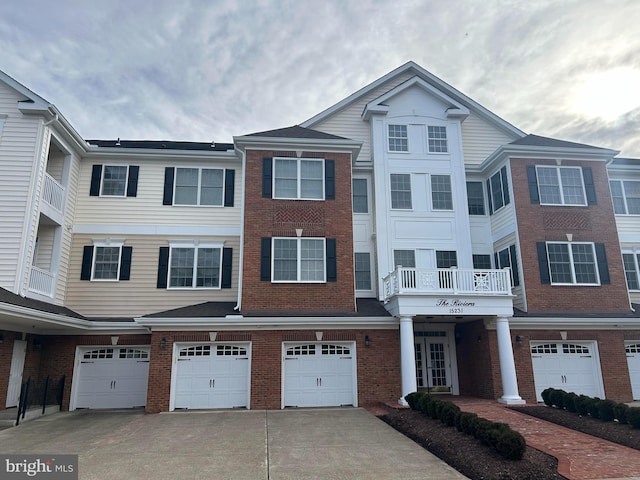 multi unit property featuring a garage, brick siding, and driveway