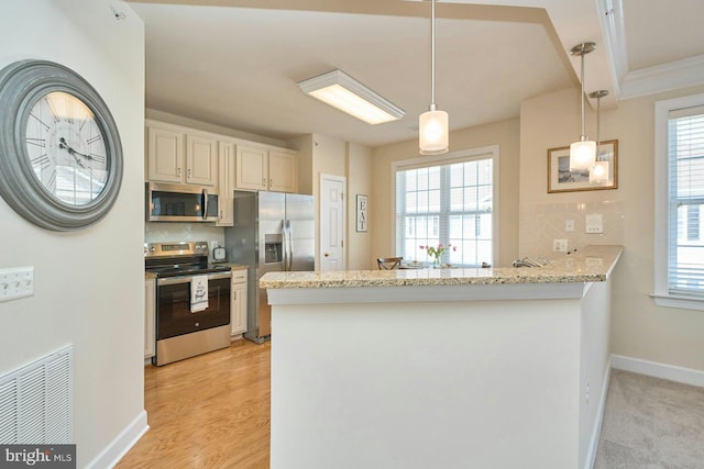 kitchen featuring light stone counters, visible vents, a peninsula, appliances with stainless steel finishes, and decorative light fixtures