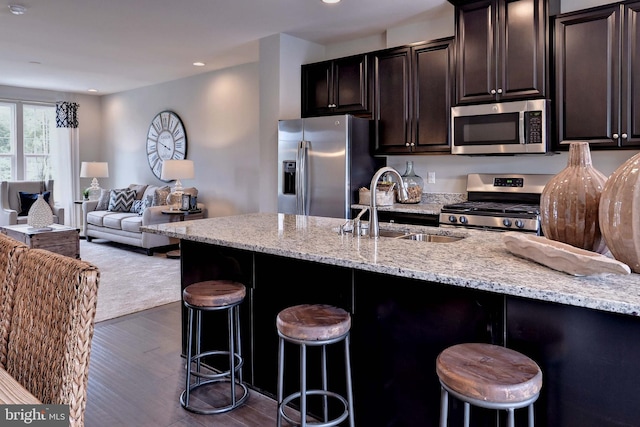 kitchen featuring light stone countertops, appliances with stainless steel finishes, a breakfast bar, and sink