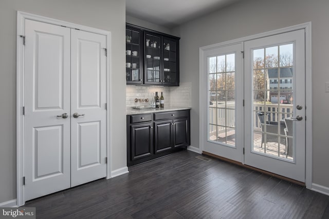 bar with tasteful backsplash, dark hardwood / wood-style floors, and light stone counters