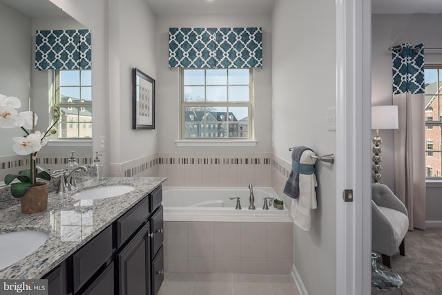 bathroom featuring tiled tub, vanity, and tile patterned floors