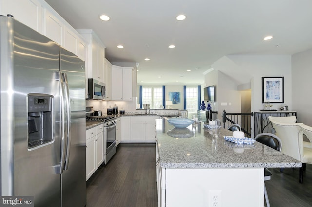 kitchen featuring stainless steel appliances, a center island, white cabinets, and a kitchen bar