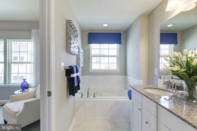 bathroom with vanity and tiled bath