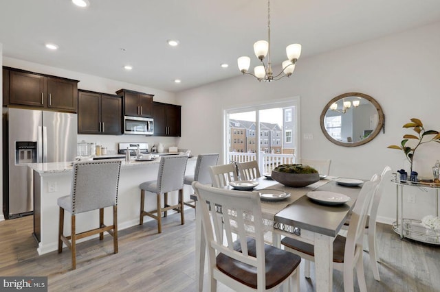 dining space with an inviting chandelier and light hardwood / wood-style flooring