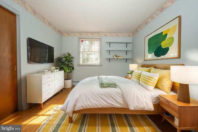 bedroom featuring baseboard heating and light hardwood / wood-style flooring