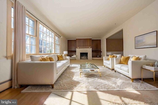 living room featuring a brick fireplace, a baseboard radiator, and light wood-type flooring