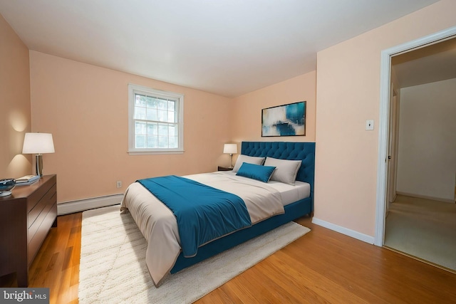 bedroom featuring a baseboard heating unit and light wood-type flooring