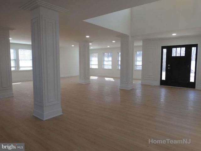 entryway with light hardwood / wood-style flooring, a wealth of natural light, and ornate columns