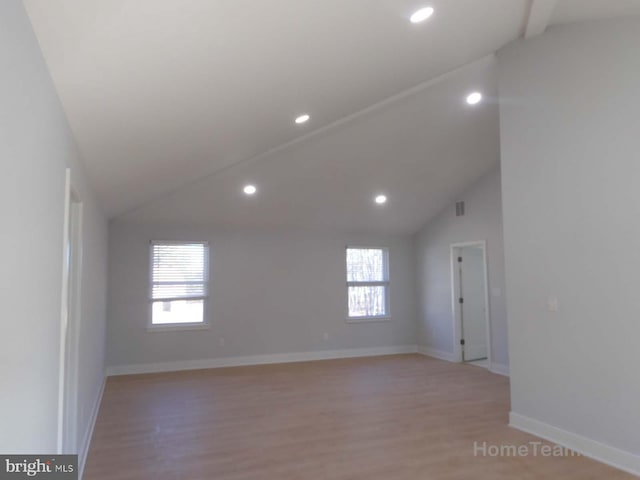 unfurnished room with a healthy amount of sunlight, vaulted ceiling, and light wood-type flooring