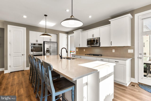 kitchen featuring white cabinetry, appliances with stainless steel finishes, a kitchen island with sink, and sink