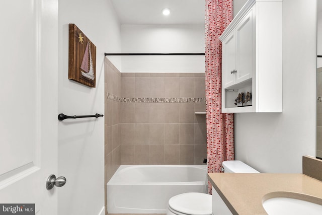 full bathroom featuring vanity, tiled shower / bath, and toilet