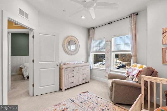 bedroom with a nursery area, ceiling fan, and light carpet