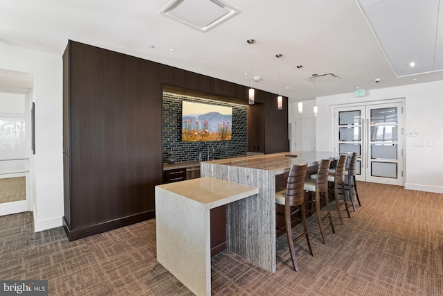 bar featuring pendant lighting, dark colored carpet, dark brown cabinets, and wood walls