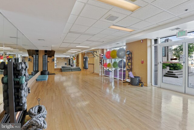 exercise room featuring french doors, a paneled ceiling, and light hardwood / wood-style flooring