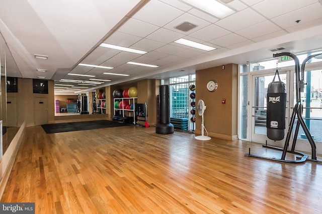 workout area featuring wood-type flooring and a paneled ceiling