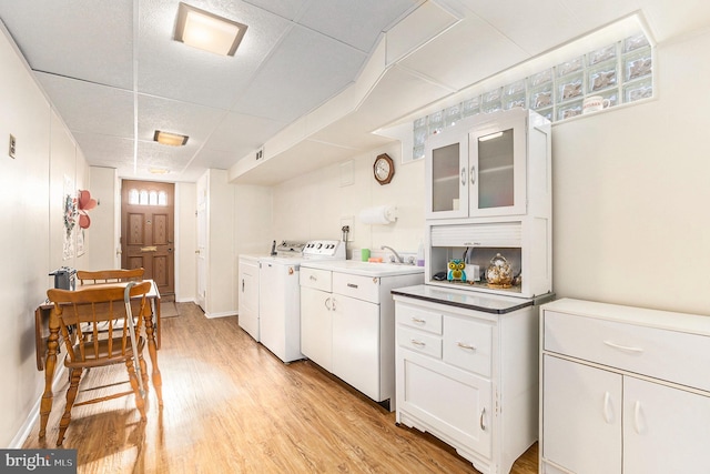 kitchen with a paneled ceiling, white cabinets, washer and clothes dryer, and light hardwood / wood-style flooring