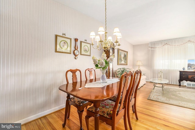 dining room with lofted ceiling, hardwood / wood-style flooring, and an inviting chandelier