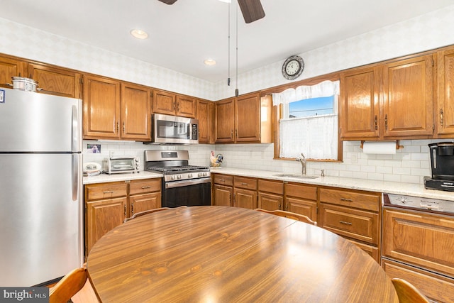 kitchen featuring sink, tasteful backsplash, appliances with stainless steel finishes, ceiling fan, and light stone countertops