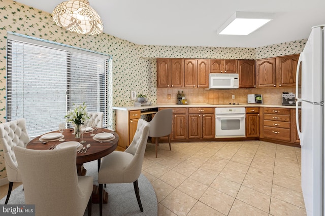 kitchen featuring backsplash, white appliances, hanging light fixtures, and light tile patterned floors