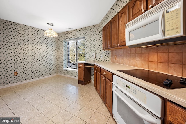 kitchen featuring light tile patterned floors, white appliances, decorative light fixtures, and decorative backsplash