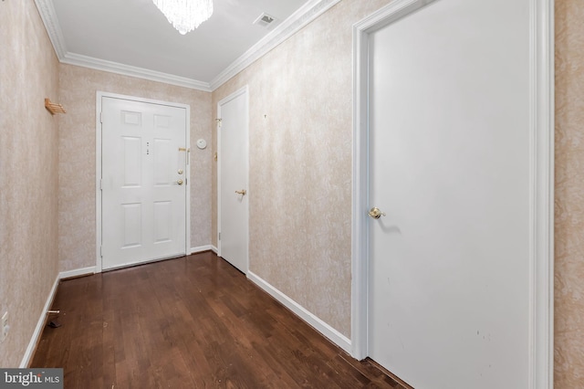 entryway with dark wood-type flooring, ornamental molding, and an inviting chandelier