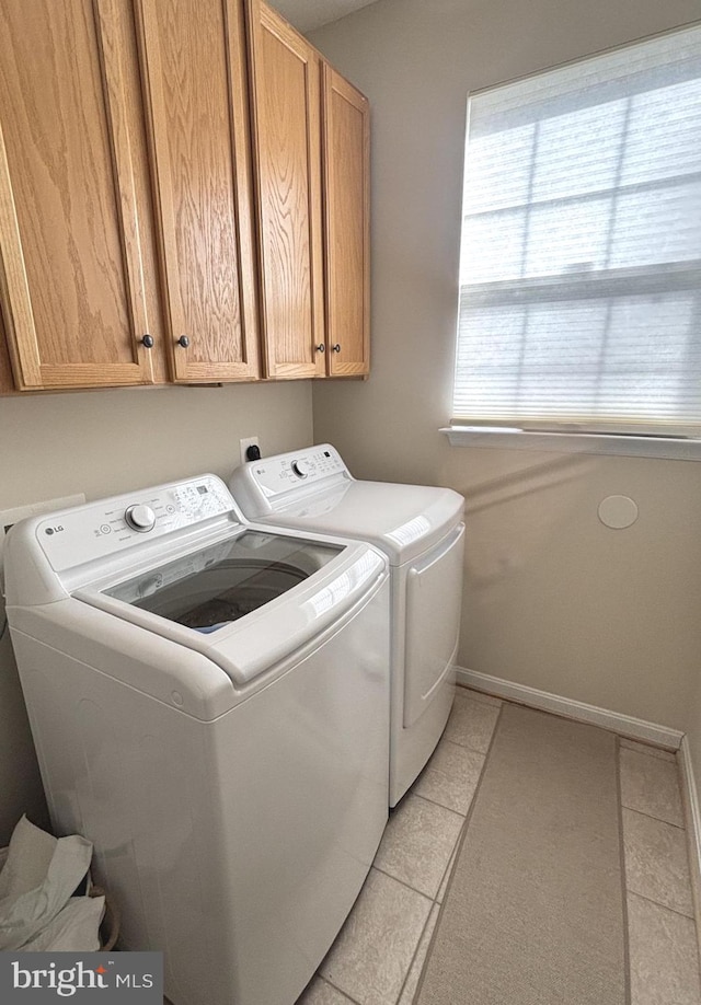 washroom featuring washer and clothes dryer, cabinets, and light tile patterned flooring