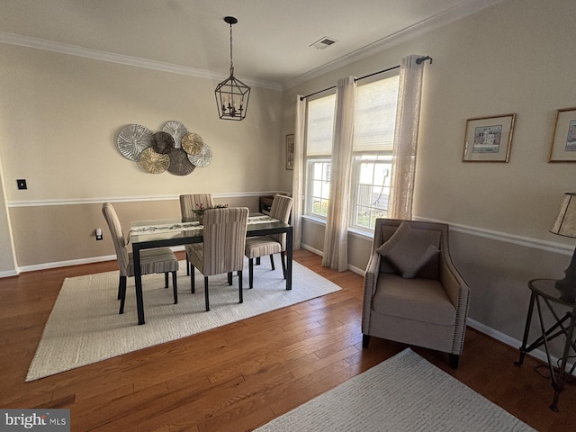 dining space featuring dark hardwood / wood-style flooring, a notable chandelier, and crown molding