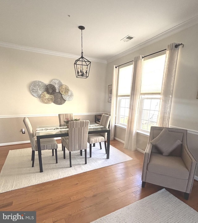 dining space featuring crown molding, hardwood / wood-style floors, and a notable chandelier