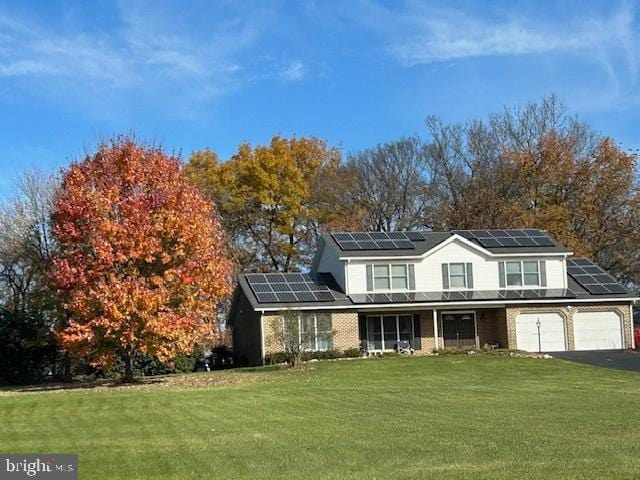 view of front of house with a garage, a front yard, and solar panels