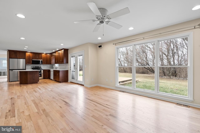 kitchen featuring a center island, light hardwood / wood-style flooring, a wealth of natural light, stainless steel appliances, and backsplash