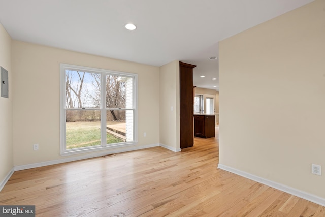 empty room with electric panel and light hardwood / wood-style flooring