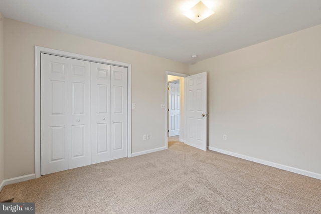 unfurnished bedroom featuring light colored carpet and a closet