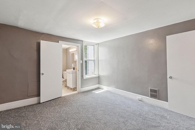 unfurnished bedroom featuring connected bathroom and carpet flooring