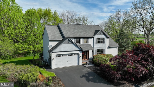 traditional home featuring roof with shingles, a garage, and aphalt driveway