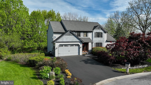 traditional-style house with an attached garage, a shingled roof, driveway, and a front lawn
