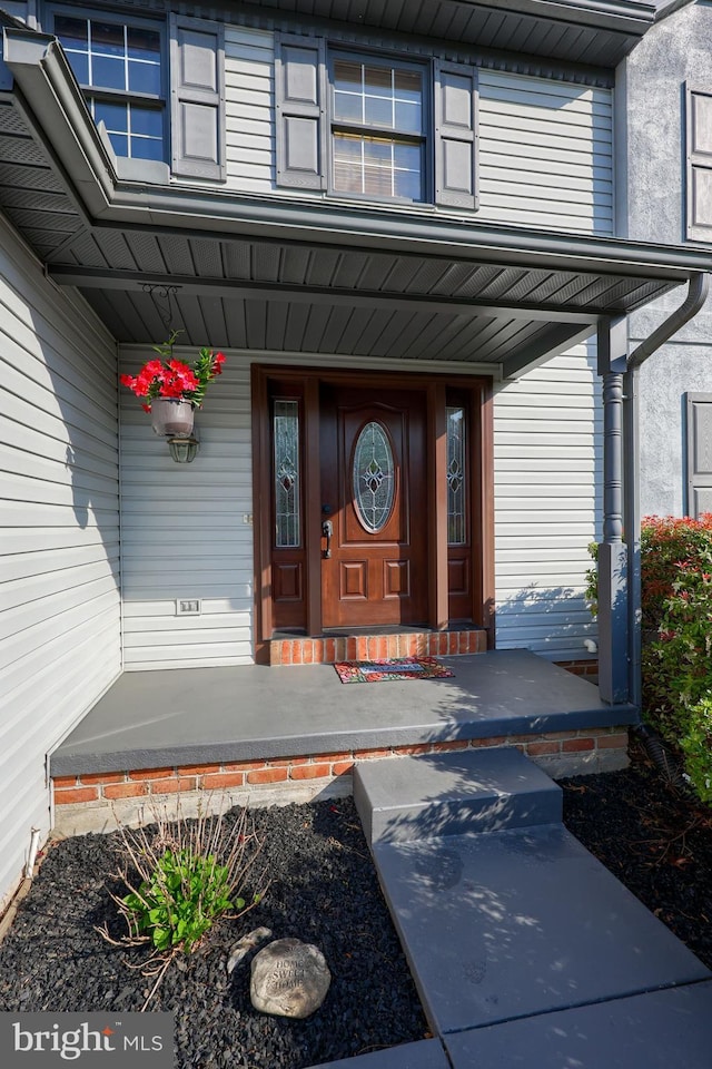 view of exterior entry featuring a porch and stucco siding