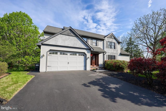 traditional-style house with driveway, a shingled roof, and an attached garage