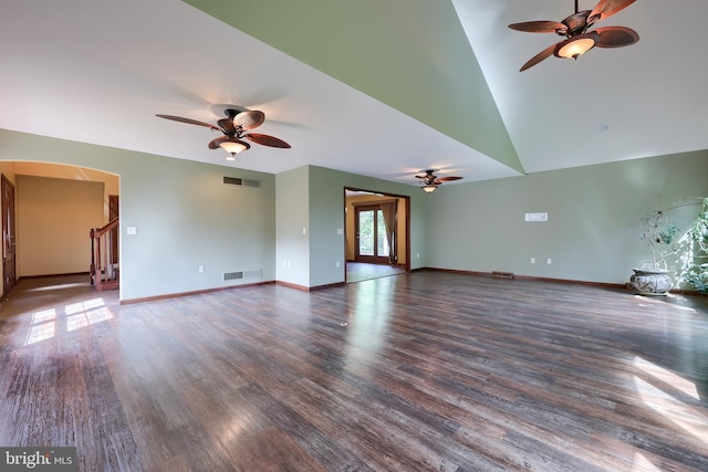 unfurnished living room with wood finished floors, stairway, ceiling fan, arched walkways, and baseboards