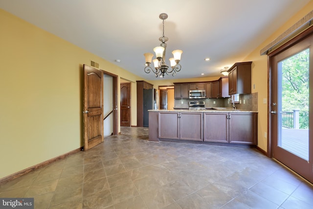 kitchen featuring a peninsula, baseboards, visible vents, a notable chandelier, and appliances with stainless steel finishes
