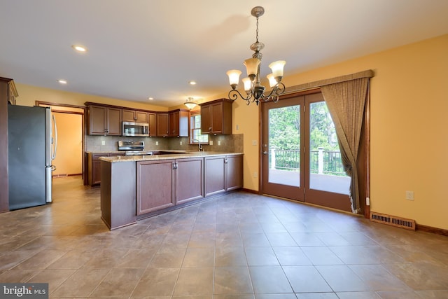 kitchen with stainless steel appliances, tasteful backsplash, a sink, and a notable chandelier