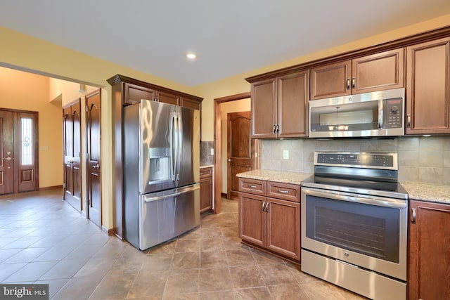kitchen featuring light stone counters, recessed lighting, tile patterned floors, backsplash, and appliances with stainless steel finishes