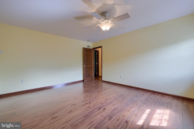 spare room with ceiling fan, baseboards, visible vents, and wood finished floors