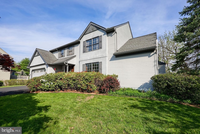 traditional-style home featuring roof with shingles, a garage, and a front lawn