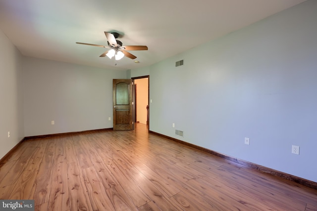 unfurnished room featuring baseboards, a ceiling fan, visible vents, and wood finished floors