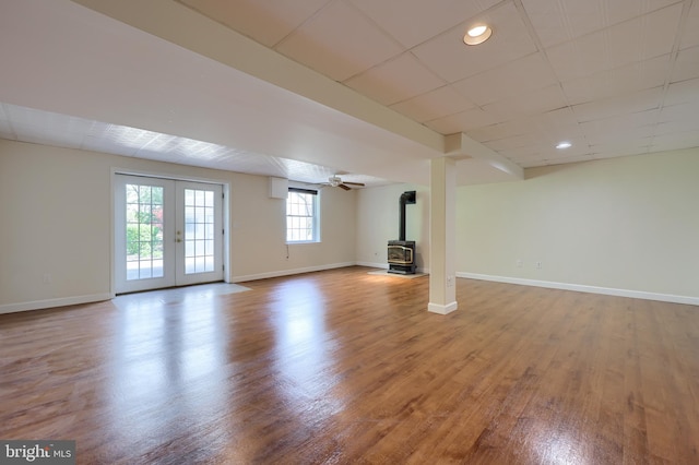 basement with a wood stove, wood finished floors, baseboards, and french doors