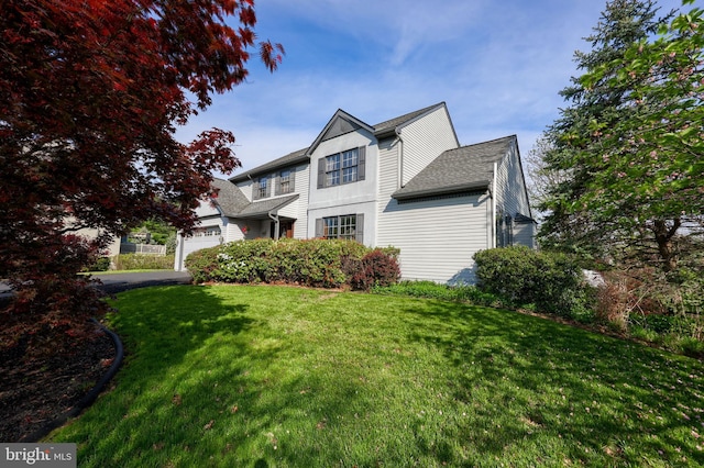 view of front of home featuring a front lawn, roof with shingles, an attached garage, and aphalt driveway