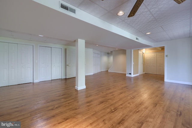 finished basement with baseboards, visible vents, and wood finished floors