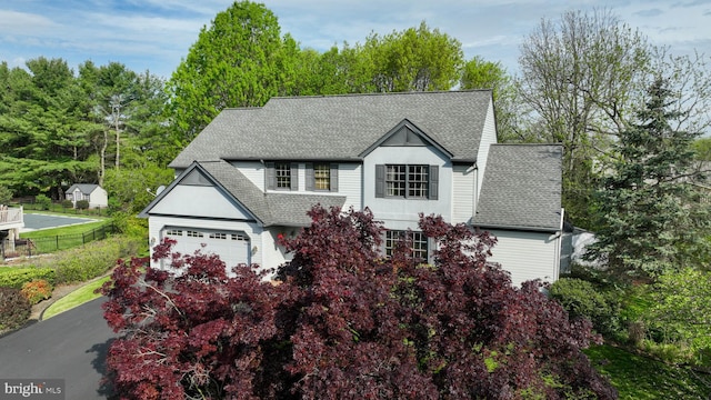 colonial house featuring a shingled roof and fence