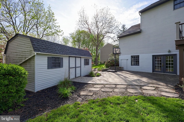 back of house with a patio, roof with shingles, french doors, and an outbuilding