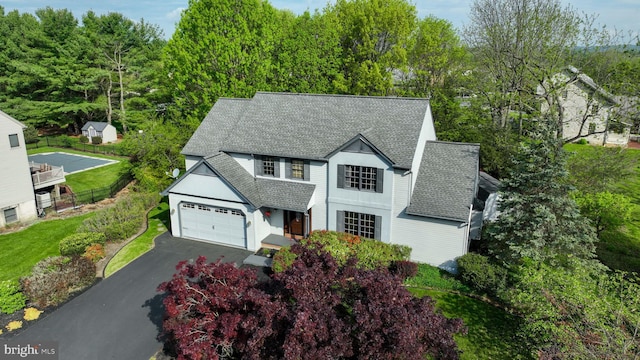 view of front of home with roof with shingles, a garage, fence, and aphalt driveway